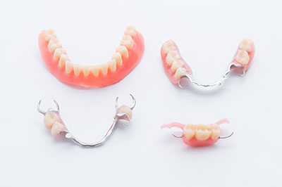 A set of four dental braces with a toothbrush and toothpaste in the background, all displayed on a white surface.