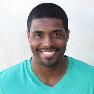 An elderly couple smiling and embracing each other in a warm, outdoor setting.