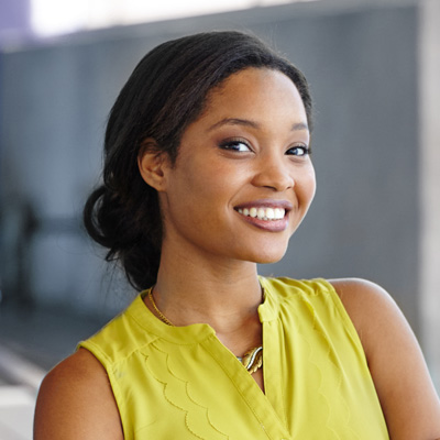 A woman with a smile, wearing a yellow top, poses for the camera.