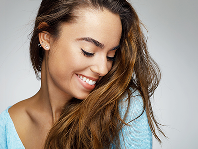 A young woman with long hair, smiling and looking to her right.