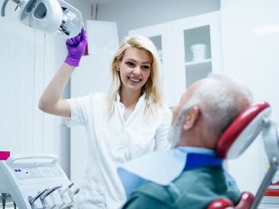 A dental professional is assisting a patient in a dental office setting.