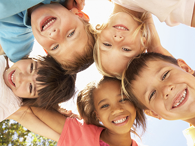 A group of children, possibly siblings, smiling and posing together for a photo in an outdoor setting.